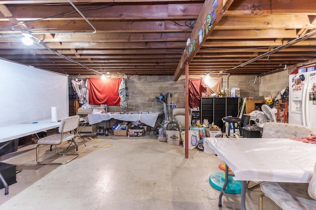 unfinished basement with white fridge with ice dispenser