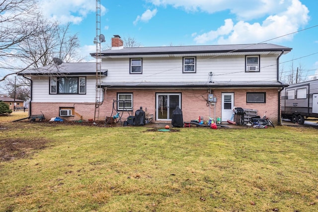 back of house featuring a chimney, a lawn, and brick siding