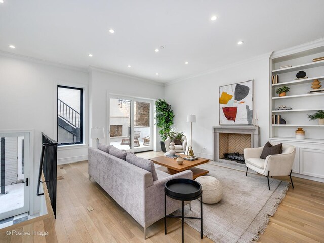 living room with recessed lighting, a premium fireplace, baseboards, ornamental molding, and light wood finished floors