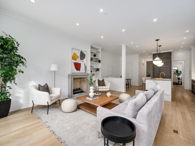 living room featuring crown molding, light wood finished floors, recessed lighting, a high end fireplace, and baseboards