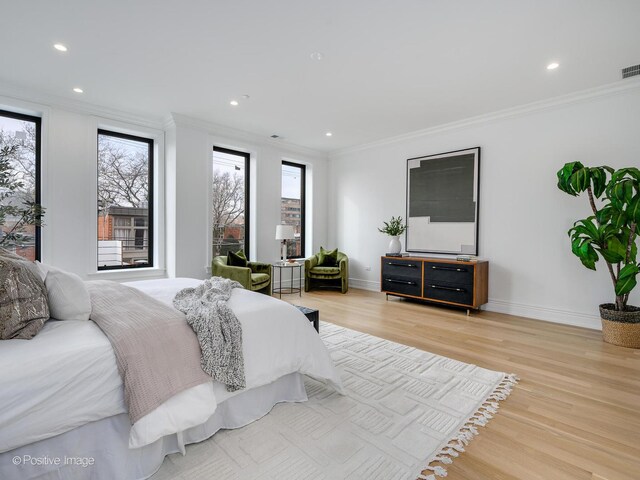 bedroom with light wood-style floors, multiple windows, ornamental molding, and visible vents