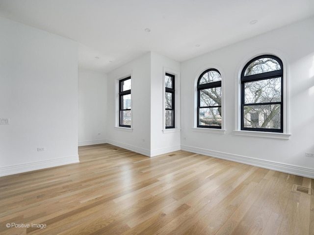 unfurnished room with light wood finished floors, baseboards, and visible vents