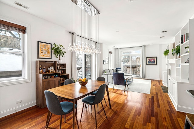 dining area with baseboards, dark wood-style flooring, visible vents, and a healthy amount of sunlight