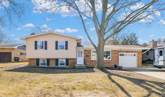 tri-level home featuring a garage, a front yard, concrete driveway, and brick siding