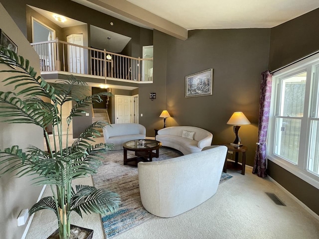 carpeted living area with lofted ceiling with beams, visible vents, and baseboards