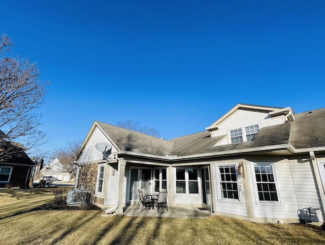 back of property featuring a patio area, a lawn, and roof with shingles