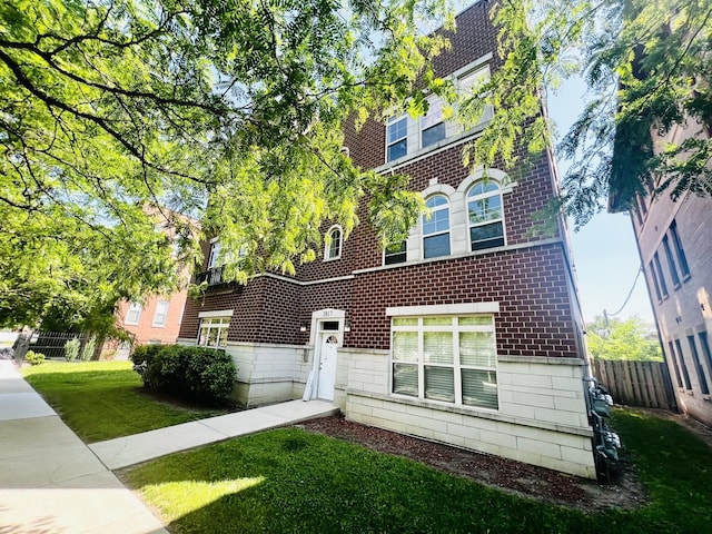 view of front of home featuring brick siding, a front yard, and fence