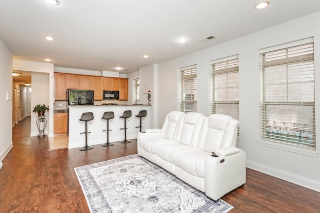 living room with dark wood-style floors, visible vents, recessed lighting, and baseboards