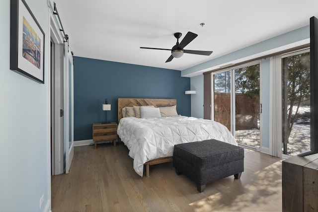 bedroom featuring a barn door, baseboards, access to outside, and dark wood-type flooring