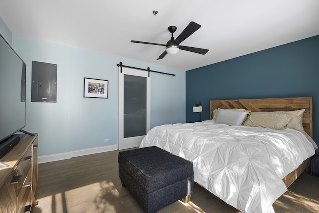 bedroom featuring a barn door, a ceiling fan, baseboards, electric panel, and dark wood-style floors