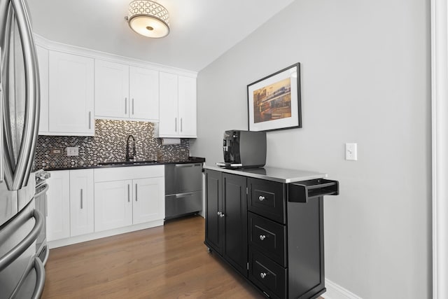 kitchen featuring dark cabinets, white cabinetry, stainless steel appliances, and a sink