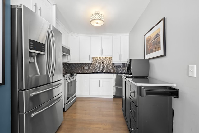 kitchen with stainless steel appliances, dark countertops, white cabinets, and a sink