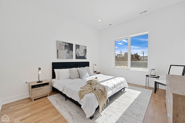 bedroom featuring light wood-style flooring, visible vents, and baseboards