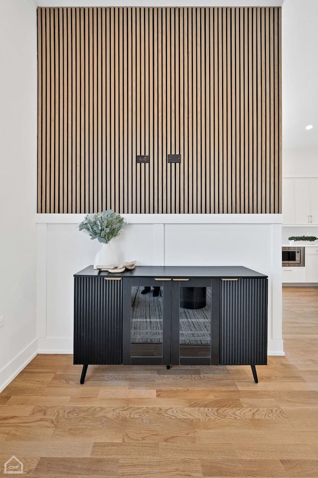 details featuring stainless steel microwave, baseboards, and wood finished floors