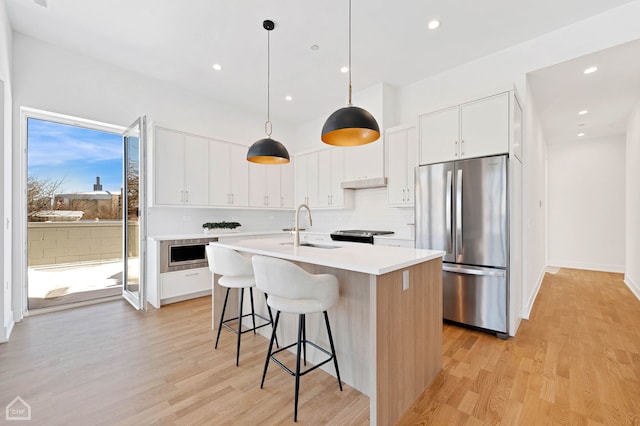 kitchen with appliances with stainless steel finishes, light countertops, an island with sink, and white cabinetry