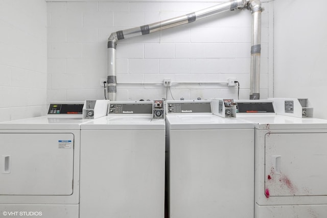 community laundry room featuring washing machine and dryer and concrete block wall