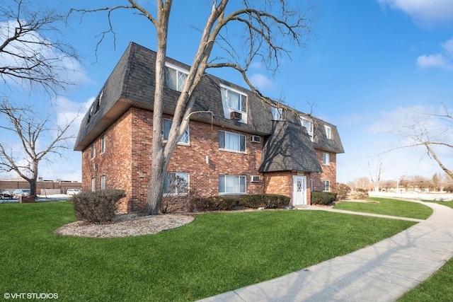 view of side of property featuring a yard, mansard roof, roof with shingles, and brick siding