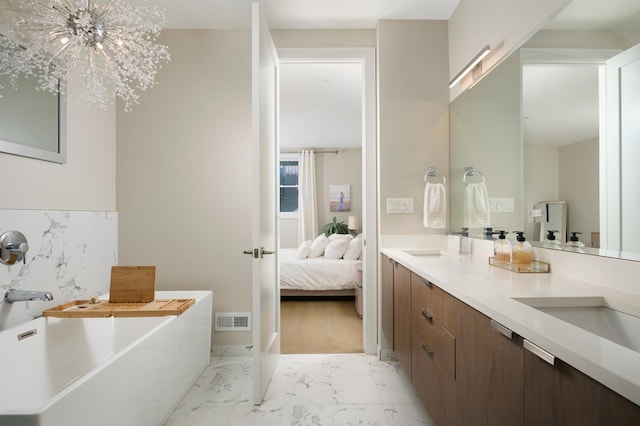 ensuite bathroom with visible vents, ensuite bathroom, marble finish floor, a freestanding bath, and a sink