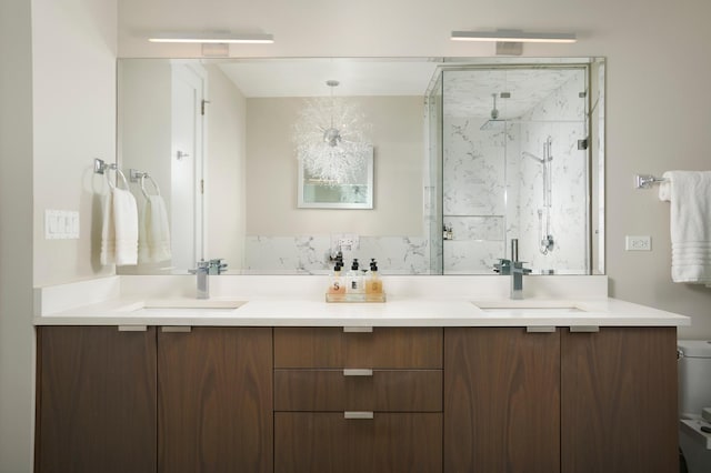 bathroom featuring toilet, double vanity, a sink, and a marble finish shower