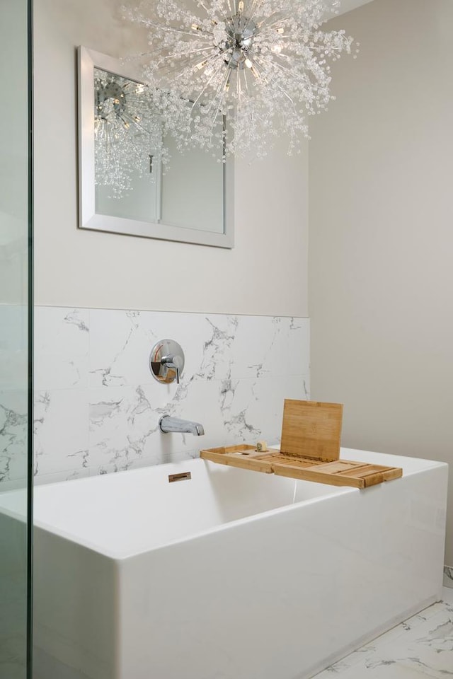 bathroom featuring marble finish floor and a soaking tub