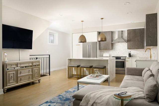 living area with light wood-style flooring, baseboards, and recessed lighting