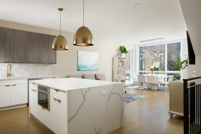 kitchen with expansive windows, a sink, backsplash, and modern cabinets