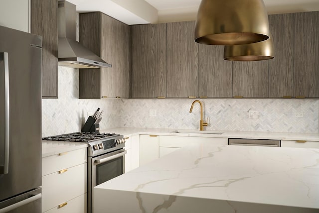 kitchen featuring decorative backsplash, appliances with stainless steel finishes, a sink, modern cabinets, and wall chimney exhaust hood