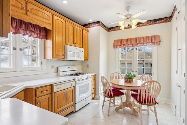 kitchen with a wealth of natural light, white appliances, light countertops, and a ceiling fan
