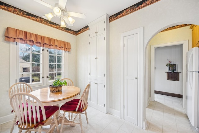 dining room featuring arched walkways, french doors, baseboards, and a ceiling fan