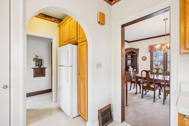 corridor featuring visible vents, arched walkways, a notable chandelier, crown molding, and light colored carpet