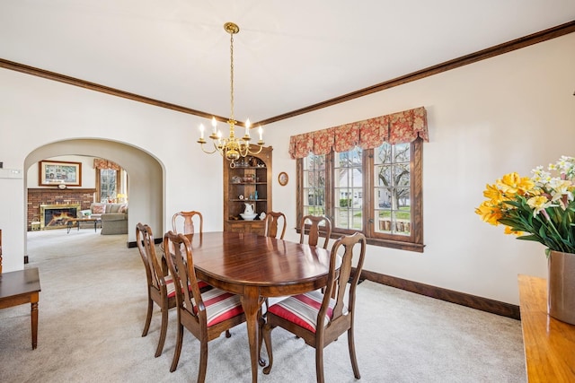 dining space featuring baseboards, ornamental molding, a chandelier, arched walkways, and light colored carpet