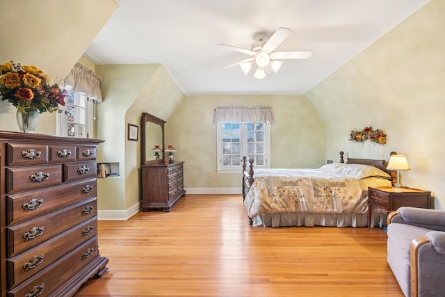 bedroom featuring light wood finished floors, baseboards, vaulted ceiling, and ceiling fan