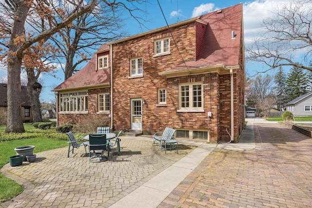 back of property featuring a patio, a shingled roof, and brick siding