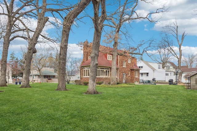 exterior space featuring a residential view, a chimney, a patio area, brick siding, and a lawn