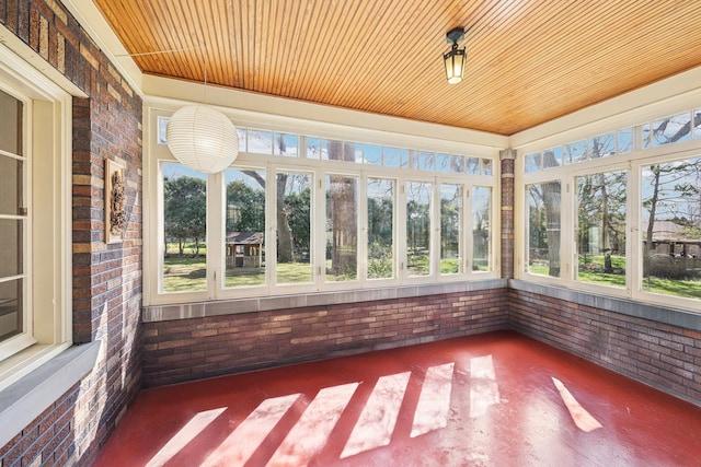 unfurnished sunroom with wood ceiling and brick wall