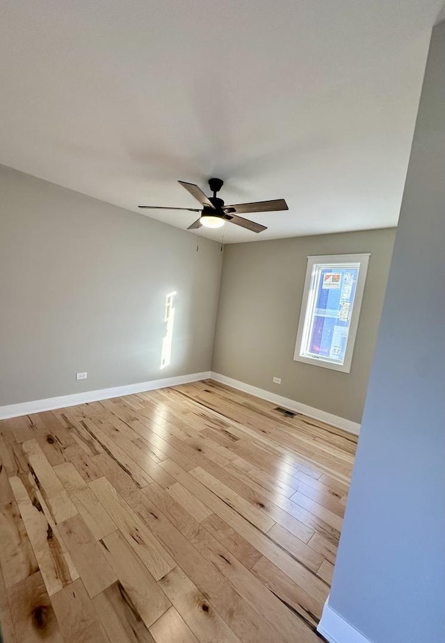 spare room featuring ceiling fan, light wood finished floors, visible vents, and baseboards