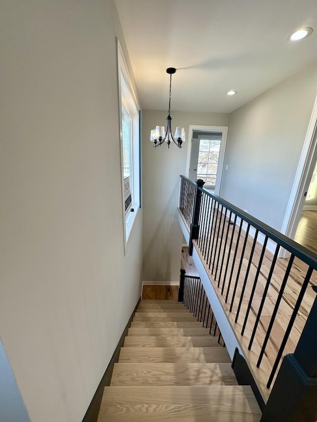 staircase featuring an inviting chandelier, baseboards, wood finished floors, and recessed lighting