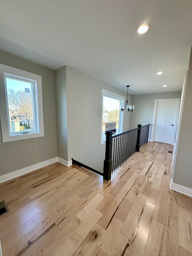 corridor featuring a notable chandelier, recessed lighting, visible vents, light wood-style floors, and baseboards