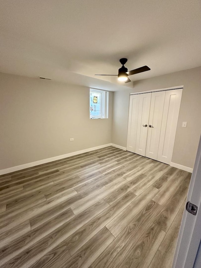 unfurnished bedroom with ceiling fan, a closet, baseboards, and wood finished floors