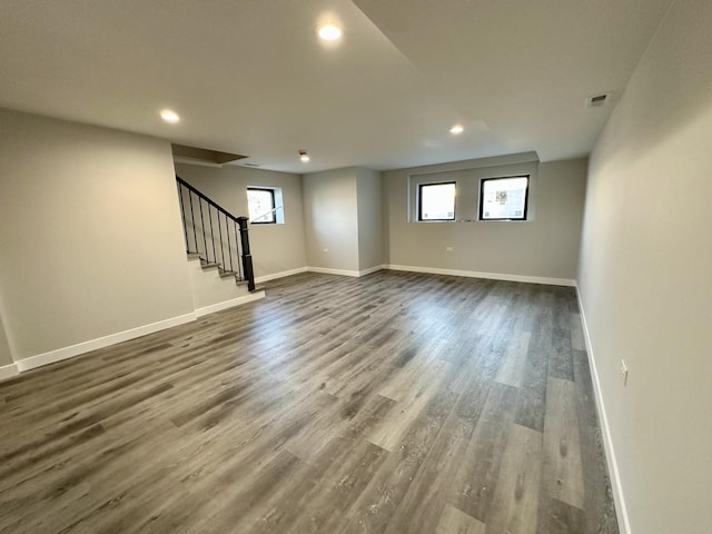 basement featuring recessed lighting, visible vents, stairway, dark wood-type flooring, and baseboards