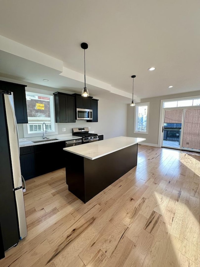 kitchen with dark cabinets, stainless steel appliances, light countertops, and a sink