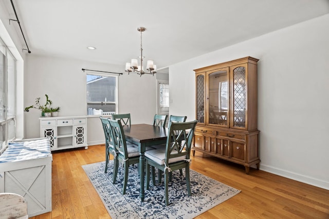 dining space with light wood finished floors, baseboards, and a notable chandelier