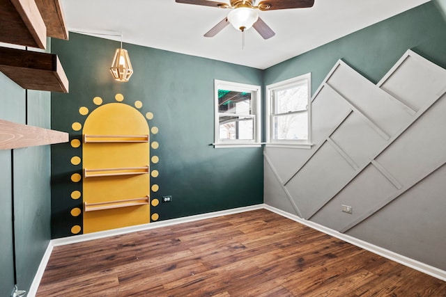 interior space featuring a ceiling fan, baseboards, and wood finished floors