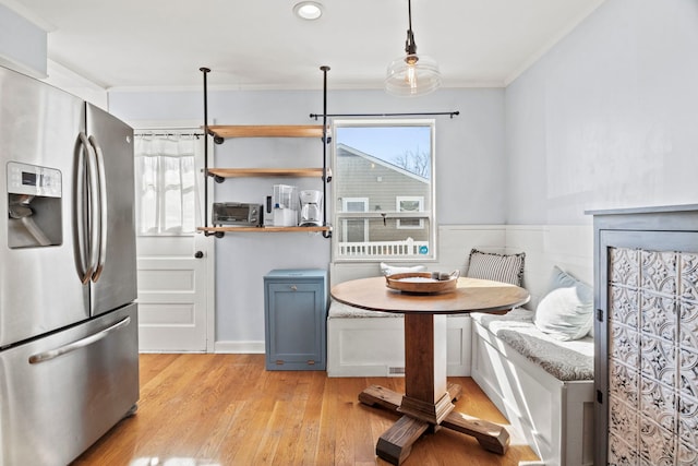 kitchen featuring light wood-style flooring, ornamental molding, stainless steel refrigerator with ice dispenser, breakfast area, and pendant lighting