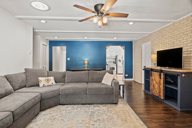 living room with ceiling fan, recessed lighting, brick wall, beamed ceiling, and dark wood finished floors