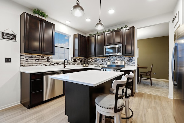 kitchen with appliances with stainless steel finishes, light countertops, dark brown cabinetry, and a kitchen breakfast bar