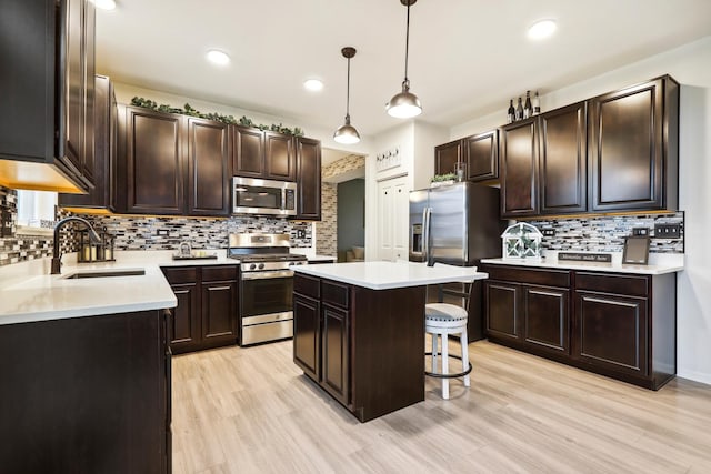 kitchen featuring light wood-style floors, a kitchen bar, stainless steel appliances, and a sink