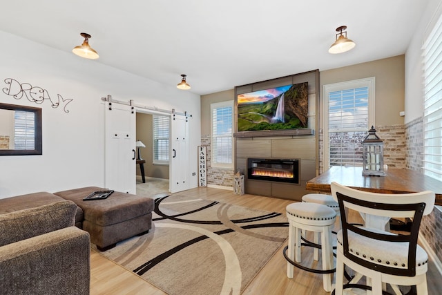 living area with plenty of natural light, a barn door, and wood finished floors