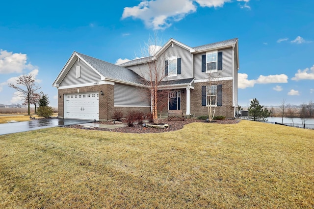 traditional home featuring a garage, driveway, a front lawn, and brick siding