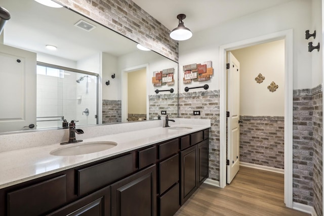 bathroom with a stall shower, visible vents, a sink, and brick wall